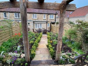 a garden with a wooden pergola in front of a house at Borough Beck Cottage in Helmsley