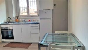a kitchen with a glass table and a refrigerator at Accomodo MIM23 Monolocale Navigli in Milan
