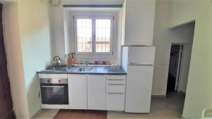 eine weiße Küche mit einer Spüle und einem Kühlschrank in der Unterkunft Accomodo MIM23 Monolocale Navigli in Mailand
