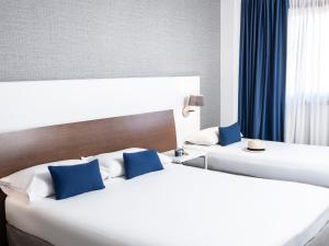 2 Betten mit blauen Kissen in einem Hotelzimmer in der Unterkunft Ibis Styles A Coruna in A Coruña