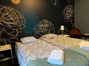 Mini-Hotel Borås Regementet في بوراس: سريرين في غرفة مع زهور مرسومة على الحائط