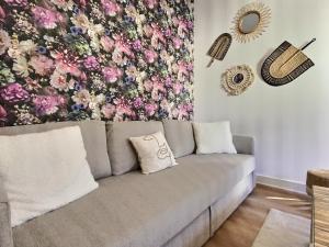 um sofá numa sala de estar com uma parede floral em Cosy Break Jardins des plantes em Le Mans