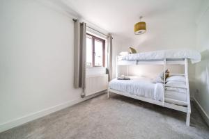 a white bedroom with a bunk bed and a window at Venn Down Lakes in Boscastle