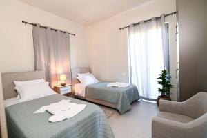 um quarto com 2 camas, uma cadeira e uma janela em Villas Thalia em Zakynthos Town