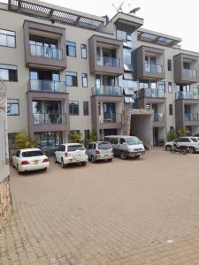 a parking lot with cars parked in front of a building at Ella Apartment Namirembe Road in Kampala
