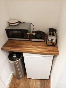 a counter with a microwave and a toaster and a trash can at Mezzanine style studio apartment 8 in London