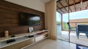 a living room with a television on a wall at Imbassaí Village Solaris in Imbassai