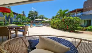- Silla de mimbre con almohadas en el patio en Imbassaí Village Solaris, en Imbassai