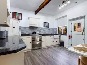 Una cocina con gabinetes blancos y un horno de estufa. en 1 King Street Accommodation, en Delph