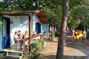 un grupo de personas sentadas en una mesa fuera de una casa en Country Camp Campeggio Paradiso en Viareggio