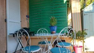stół i krzesła na ganku z zieloną okiennicą w obiekcie Mediterranee Paradise w miejscowości Saint-Raphaël