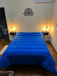 a large blue bed in a bedroom with two lamps at Caseros 139 in General Alvear