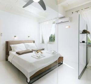 a white bedroom with a bed and a glass wall at Villa Olympia in the palm trees in Pitsidia
