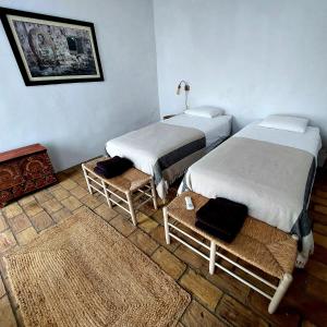 two beds in a room with two chairs and a rug at Casa Bablou in Sanlúcar de Barrameda