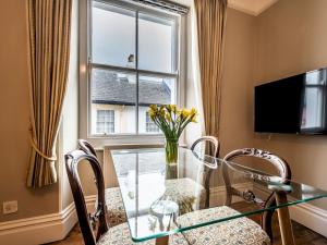 a dining room with a glass table and chairs and a window at Pass the Keys Characterful period home in heart of Chagford in Chagford