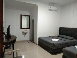 1 dormitorio con cama, escritorio y espejo en Nexdeco House Homestay Syariah Solo, en Solo