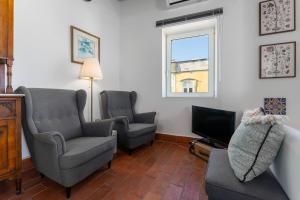 een woonkamer met 2 stoelen en een televisie bij Town House Olhão 11 in Olhão