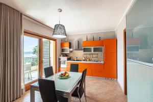 una cucina con armadi arancioni e un tavolo con frutta di Appartamenti Le Maree a La Maddalena
