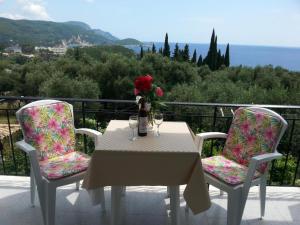 a table with two chairs and a vase with flowers on it at Katerina Studios in Paleokastritsa