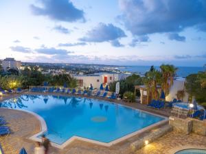 een groot zwembad met stoelen en de oceaan op de achtergrond bij Sunshine Village Hotel in Chersonissos