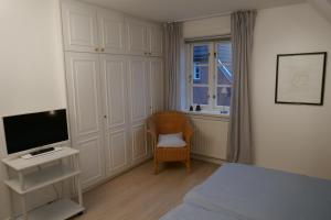 1 dormitorio con 1 cama, TV y silla en Haus Sommerfrische, en Südstrand