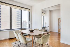 a dining room with a table and chairs and large windows at Midtown East 3BR w Doorman Gym nr Bloomingdales NYC-915 in New York