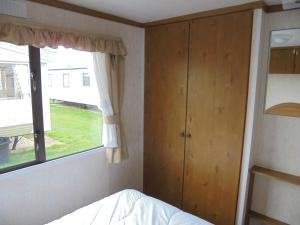 a bedroom with a bed and a window at 6 Berth on Coral Beach (Carnaby Siesta) in Ingoldmells