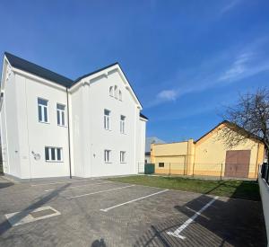 a white building in a parking lot at Apartman 7- Vila Stefanik in Trenčianska Teplá