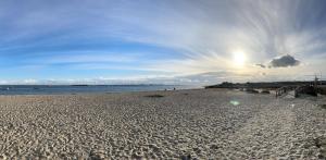 a sandy beach with the sun in the sky at Vista Mar Aldeia de Marim in Marim