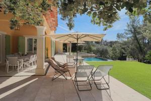 a patio with chairs and an umbrella and a pool at VILLA DES COLLINES - Absolute calm at 10' from the center in Antibes