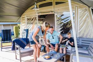 Irrel的住宿－Country Camp camping Südeifel，坐在帐篷下桌子上的女人、男人和男孩