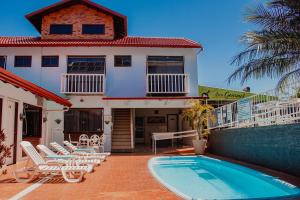 una casa con piscina frente a una casa en Hotel e Pousada Caroline, en Foz do Iguaçu