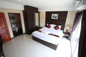 a bedroom with a large white bed with red pillows at Valhalla Pattaya Hotel in Jomtien Beach +40 photos