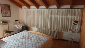 ein Schlafzimmer mit einem Bett und einem großen Fenster in der Unterkunft Casa delle Rose in Teglio