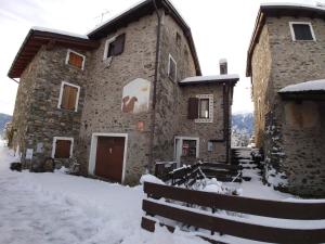 ein großes Steingebäude mit Schnee auf dem Boden in der Unterkunft Casa delle Rose in Teglio