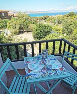 una mesa azul con platos y vasos en el balcón en La Finestra Sul Mare, en Stintino