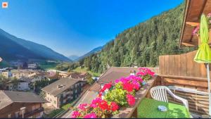 einen Balkon mit Blumen und Bergen im Hintergrund in der Unterkunft Hotel Gurschler in St. Leonhard in Passeier