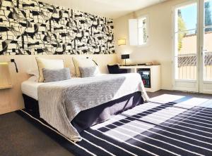 a bedroom with a bed with a black and white patterned wall at La Bastide Du Port - Hôtel de Charme in Saint-Tropez