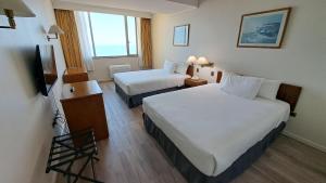 a hotel room with two beds and a television at Hotel Diego De Almagro Costanera - Antofagasta in Antofagasta