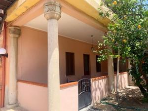 une maison avec un pilier et un balcon avec un oranger dans l'établissement Apt con portico privato vicino Cagliari Airport, à Assemini