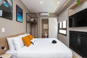 1 dormitorio con 1 cama blanca grande con almohadas de color naranja en Charlie Franca Jardim Paulista, en São Paulo