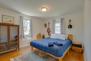 a bedroom with a bed with a blue comforter and two windows at The Titan - Pet-friendly Bungalow in Nashville