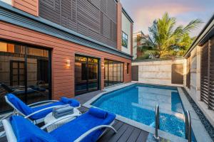 a swimming pool with blue chairs and a house at Narcissus Obhur Resort & Spa in Jeddah