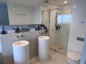 a bathroom with two sinks and a shower and a toilet at 29th floor Oracle Tower 2 stunning ocean and city views in Gold Coast