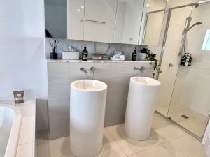 a bathroom with two white sinks and a shower at 29th floor Oracle Tower 2 stunning ocean and city views in Gold Coast