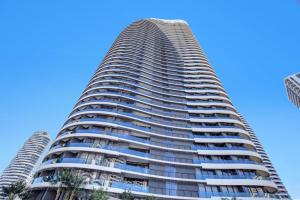 a tall building with palm trees in front of a blue sky at 29th floor Oracle Tower 2 stunning ocean and city views in Gold Coast