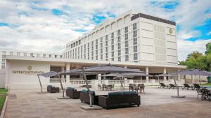 a hotel with tables and umbrellas in front of a building at InterContinental Lusaka, an IHG Hotel in Lusaka