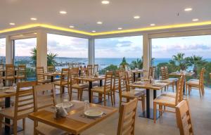 a restaurant with tables and chairs and a view of the ocean at Sunshine Village Hotel in Hersonissos