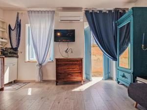 a living room with blue curtains and a dresser at Loft Francesca Old City Center in Rio Marina