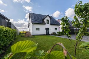 una casa blanca con techo negro en un patio en Luxus_Ferien_VILLA AMICI, en Göhren-Lebbin